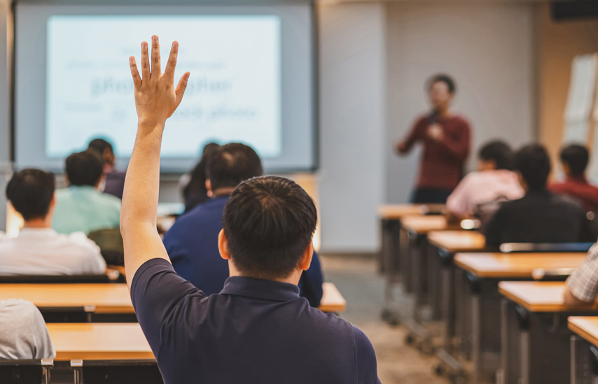 student with hand raised in lecture